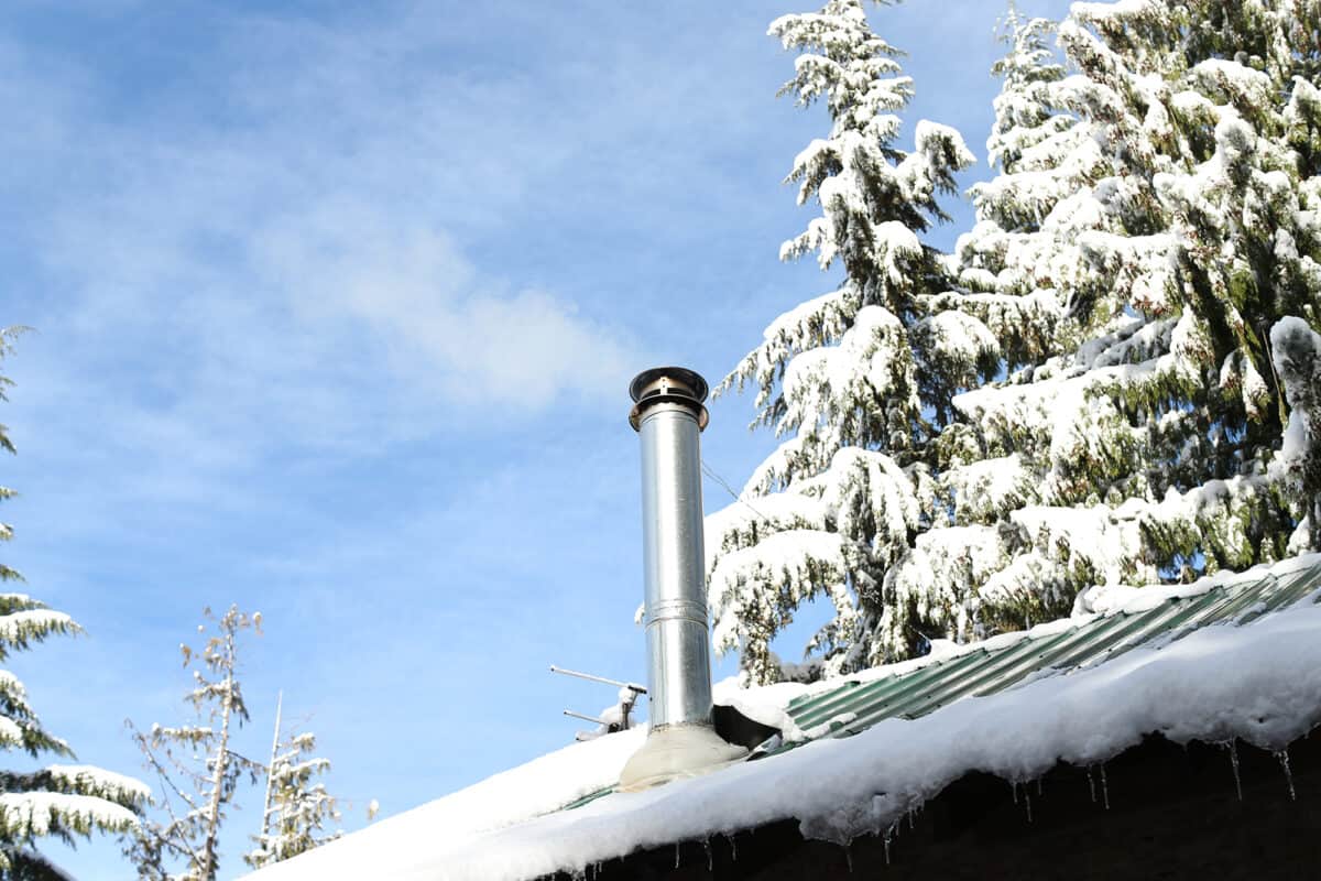chimney pipe on snowy cabin roof