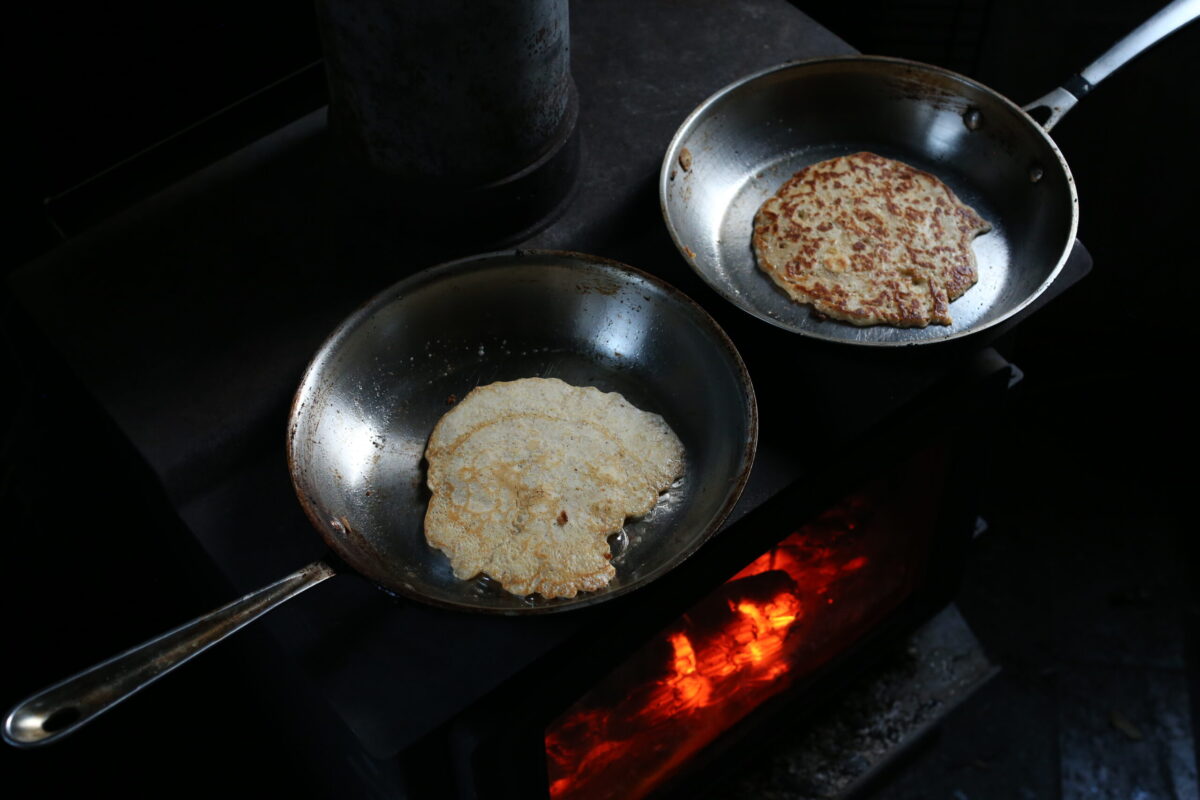 Pancakes cooking in pans on wood stove